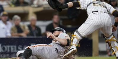 El jugador de los Gigantes de San Francisco Brandon Belt (abajo) anota en un sencillo remolcador de LaMonte Wade Jr. ante el catcher de los Padres de San Diego (arriba), en el noveno inning del juego de la MLB que enfrentó a ambos equipos, el 21 de septiembre de 2021, en San Diego. (AP/Gregory Bull)