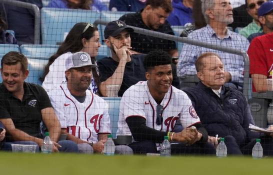 El jardinero dominicano Juan Soto, segundo desde la derecha, y el agente Scott Boras, a su derecha, se sientan en las gradas del Dodger Stadium en el partido entre los Cardenales y Los Ángeles el miércoles 6 de octubre del 2021. (AP Photo/Marcio Jose Sanchez)